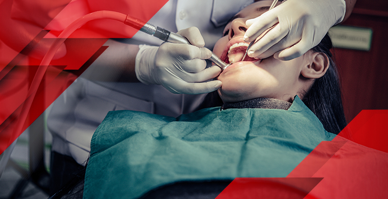 Odontologista realizando procedimento em paciente de boca aberta